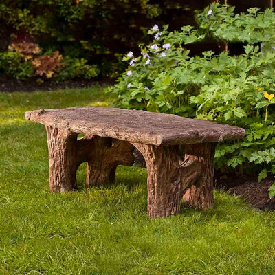 Campania International Faux Bois Bench, set in the garden to adding charm and purpose. The bench is shown in the Brownstone Patina.