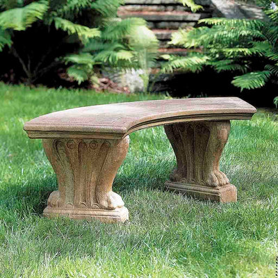 Campania International Curved West Chester Bench, set in the garden to adding charm and purpose. The bench is shown in the Aged Limestone Patina.