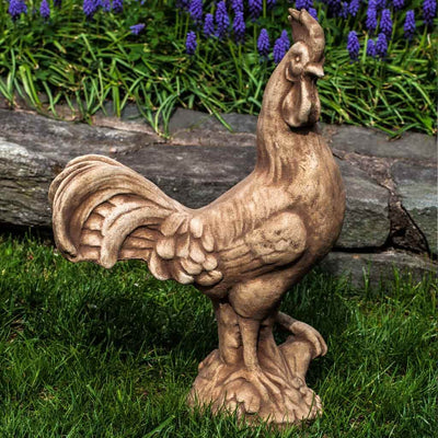 Campania International Antique Rooster Statue, set in the garden to add charm and character. The statue is shown in the Brownstone Patina.