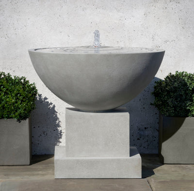 Campania International Darien Plinth Fountain, shown in hand-painted Alpine Stone, a medium green-gray patina that works well against multiple colors in the landscape.