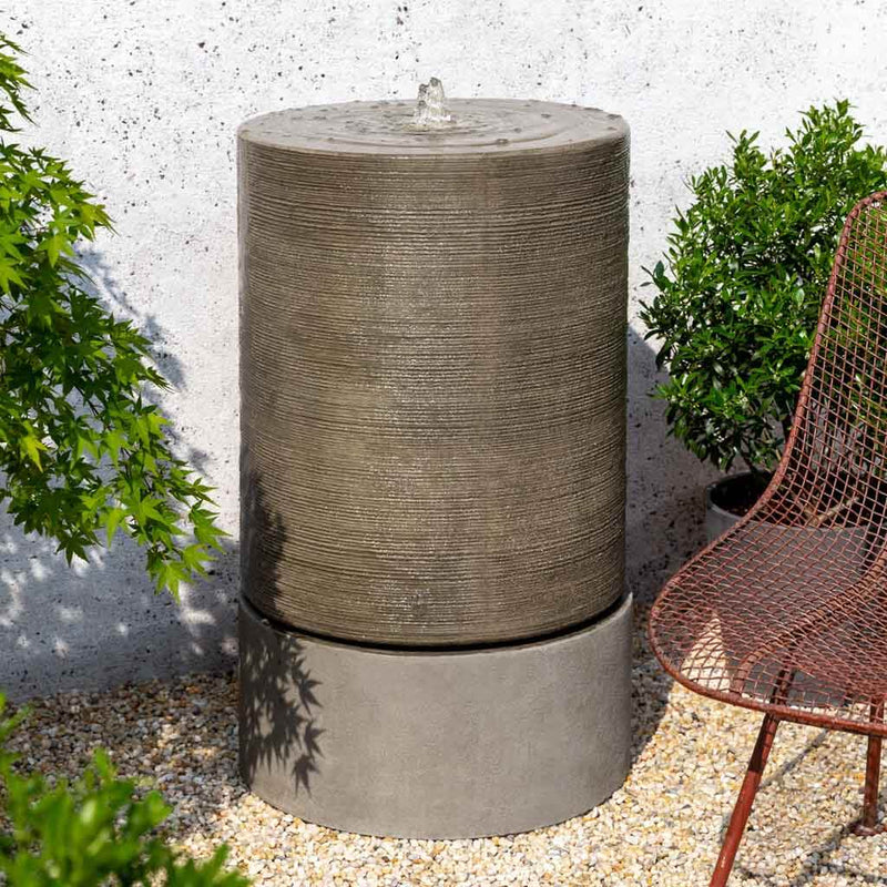 Campania International Large Cylinder Fountain, shown in hand-painted Alpine Stone, a medium green-gray patina that works well against multiple colors in the landscape.
