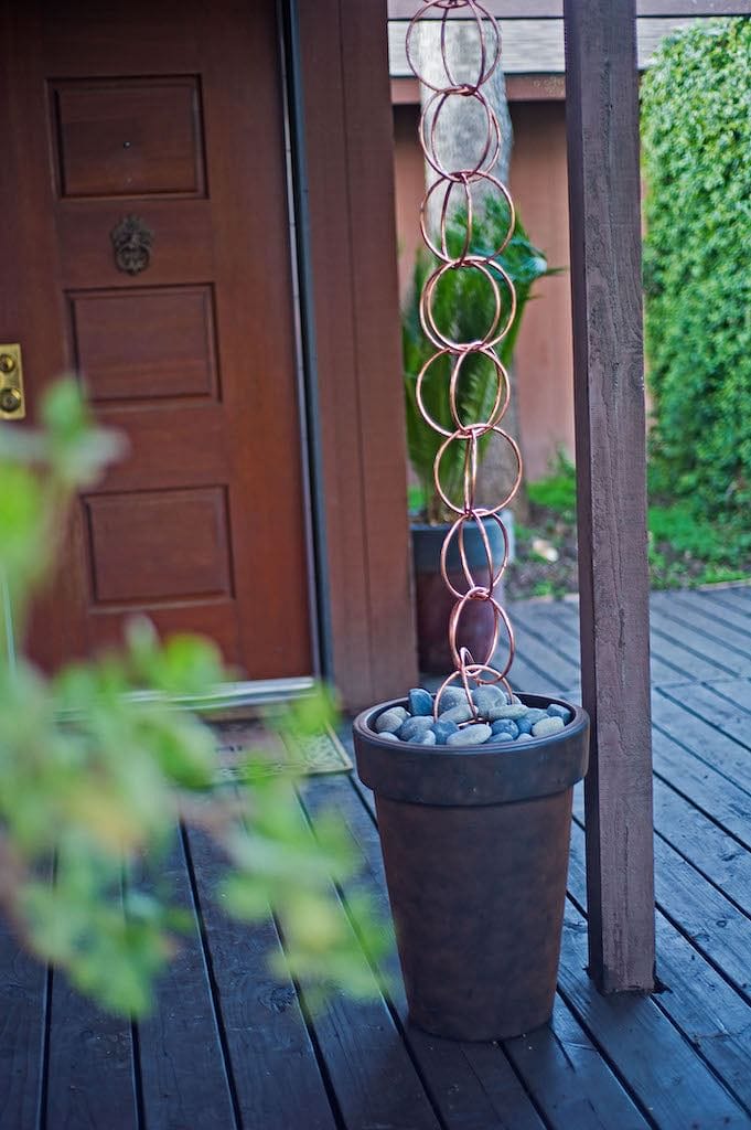 Good Directions Double Link Pure Copper 8.5 ft. Rain Chain beautifully anchored in a planter with stones.