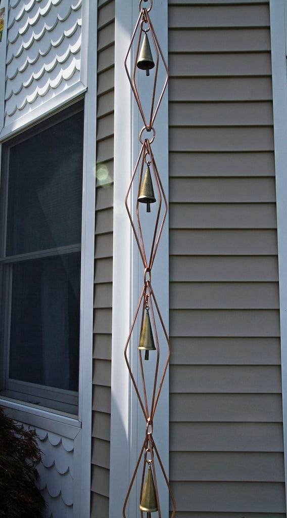 Good Directions Diamond Pure Copper 8.5 ft. Rain Chain with Bells the length of the chain against a home.