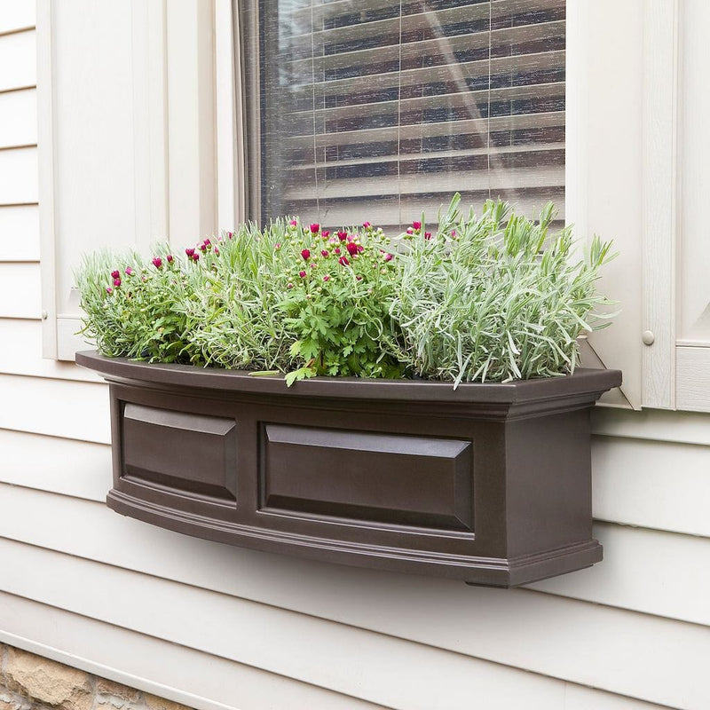 The Mayne Nantucket 3ft Window Box Planter, with a espresso finish, mounted under a window and filled with colorful flowers.