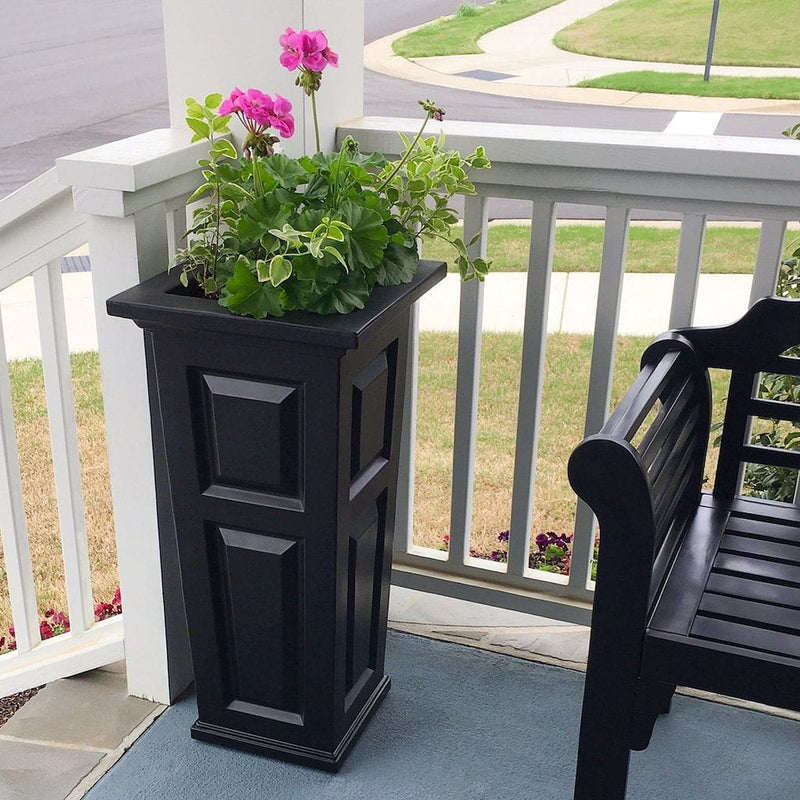 The Mayne Nantucket Tall Planter, in the black finish, planted and placed near home for curb appeal.