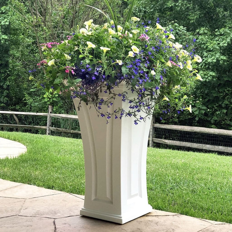 The Mayne Cambridge Tall Planter, in the white finish, planted and placed near home for curb appeal.