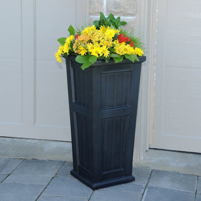 The Mayne Cape Cod Tall Planter, in the black finish, planted and placed near home for curb appeal.
