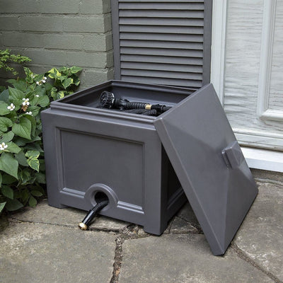 The Mayne Fairfield Garden Hose Bin in Graphite Grey, in the graphite finish,storing a hose and ready for use.