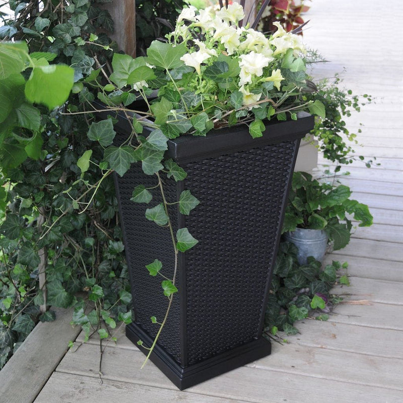 The Mayne Wellington Tall Planter, in the black finish, simply planted with flowers to add curb appeal to a front entry of a home.