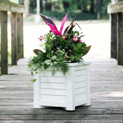 The Mayne Lakeland 16x16 Square Planter, in the white finish, planted with colorful plants and set out on a deck.