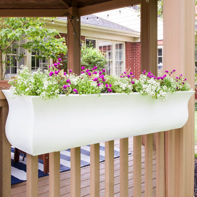 The Mayne Valencia 4ft Window Box Planter, in the white finish, planted with colorful flowers and hung on a deck railing.