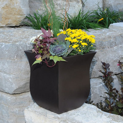 The Mayne Valencia Square Planter, in the espresso finish, planted with a combination of flowers and foliage and set in the garden.