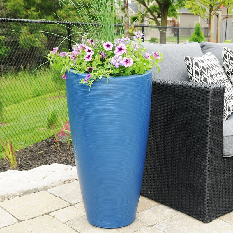 The Mayne Modesto Tall Planter, in the neptune blue finish, giving a pop of bright blue color against an outdoor sofa.