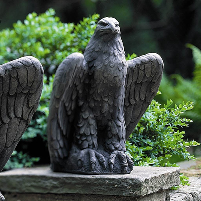 Campania International Eagle Looking Left and Right Statue, set in the garden to add charm and character. The statue is shown in the Aged Limestone Patina.