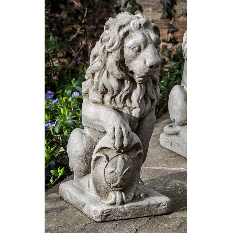 Campania International Small Classic Lion Facing Left Statue, set in the garden to add charm and character. The statue is shown in the Greystone Patina.