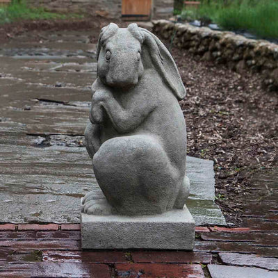 Campania International Newport Rabbit Facing Left Statue, set in the garden to add charm and character. The statue is shown in the Greystone Patina.