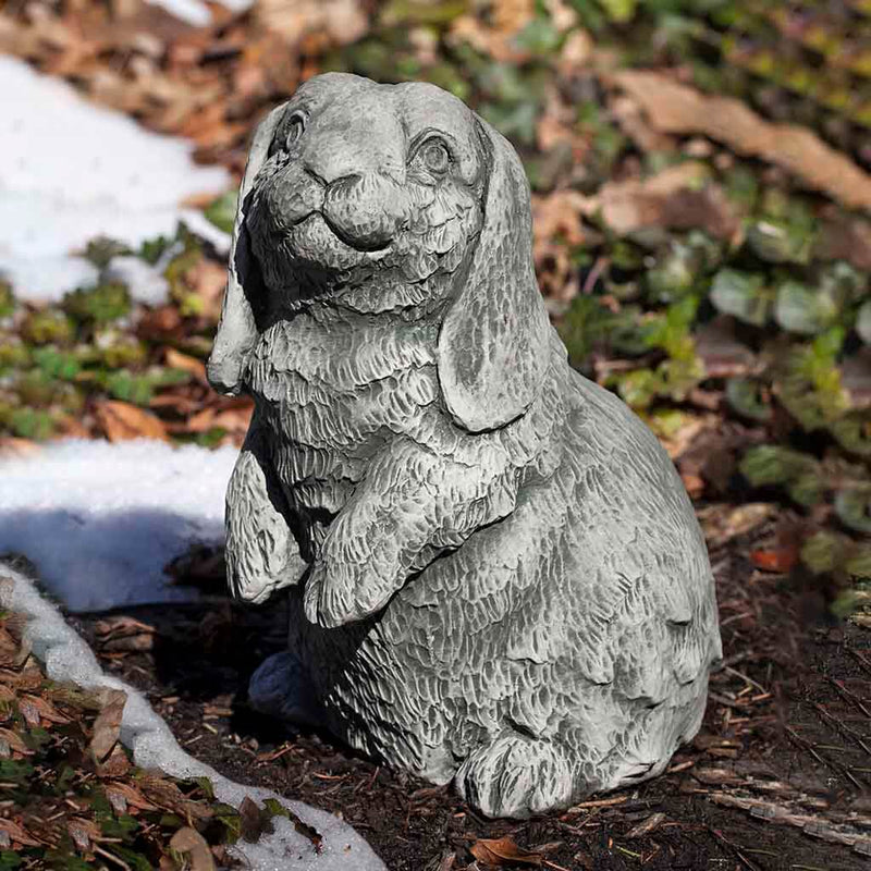 Campania International Lop-Eared Standing Bunny Statue, set in the garden to add charm and character. The statue is shown in the Alpine Stone Patina.
