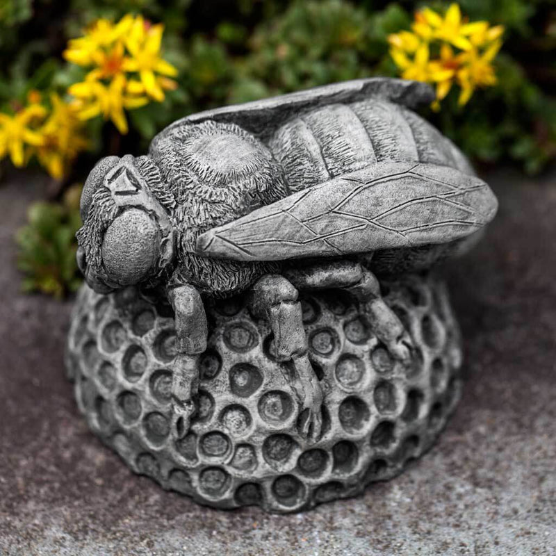 Campania International Honey Bee Statue, set in the garden to add charm and character. The statue is shown in the Alpine Stone Patina.