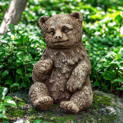 Campania International Bear Cub Statue, set in the garden to add charm and character. The statue is shown in the Brownstone Patina.