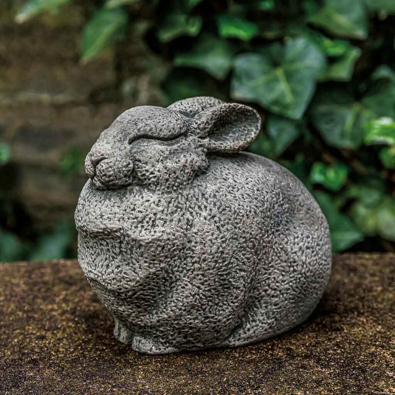Campania International Stone Bunny Statue, set in the garden to add charm and character. The statue is shown in the Greystone Patina.