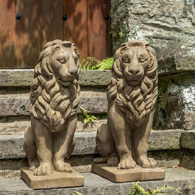 Campania International Sentry Lion Facing Left Statue, set in the garden to add charm and character. The statue is shown in the Aged Limestone Patina.