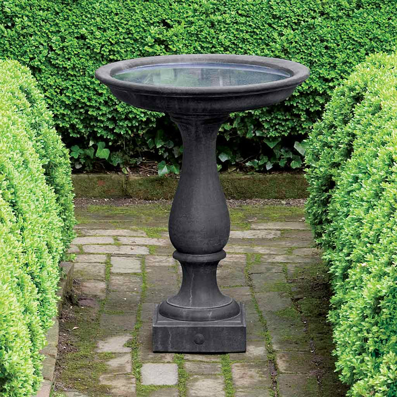 Campania International Candlestand Birdbath, set in the garden to adding charm and purpose. The birdbath is shown in the Nero Nuovo Patina.