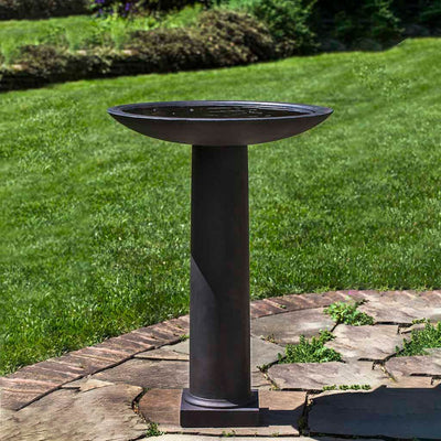 Campania International Metropolitan Birdbath, set in the garden to adding charm and purpose. The birdbath is shown in the Nero Nuovo Patina.