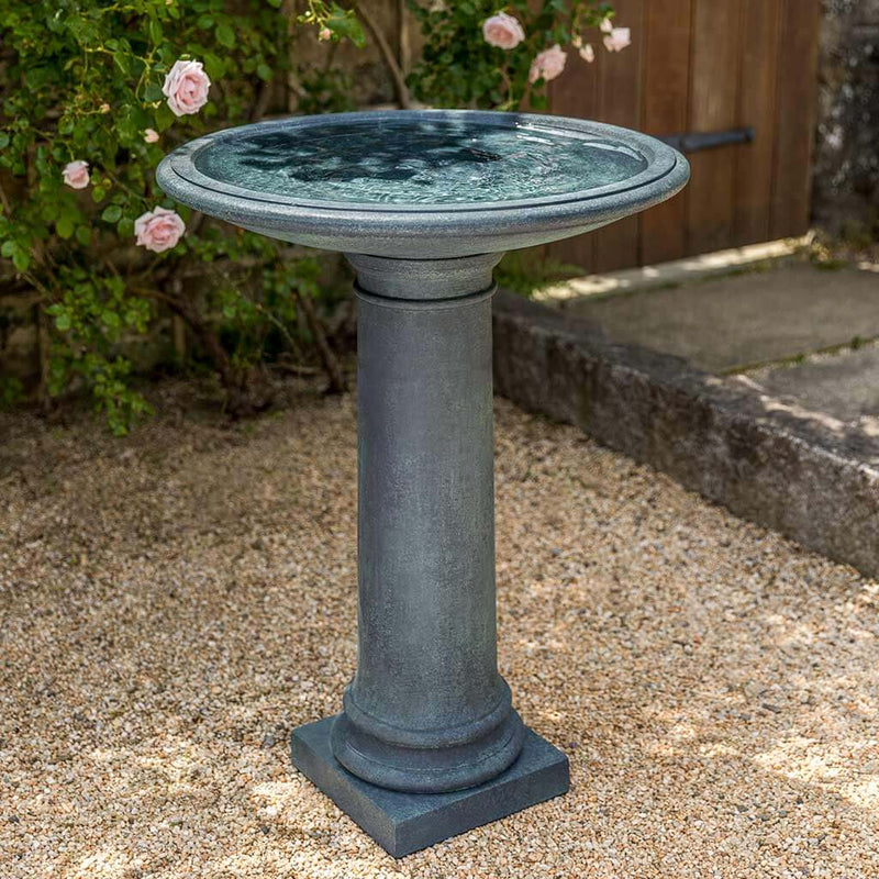 Campania International The Hampton Birdbath, set in the garden to adding charm and purpose. The birdbath is shown in the Lead Antique Patina.