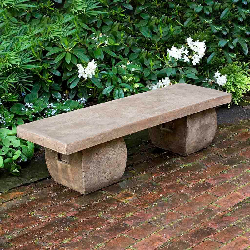 Campania International Ryokan Bench, set in the garden to adding charm and purpose. The bench is shown in the Brownstone Patina.