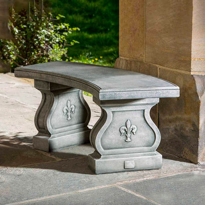 Campania International Fleur De Lys Curved Bench, shown in the Alpine Stone color, highlighting and enriching the details of the cast stone.