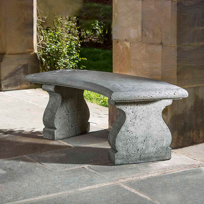 Campania International Provencal Curved Bench, set in the garden to adding charm and purpose. The bench is shown in the Alpine Stone Patina.