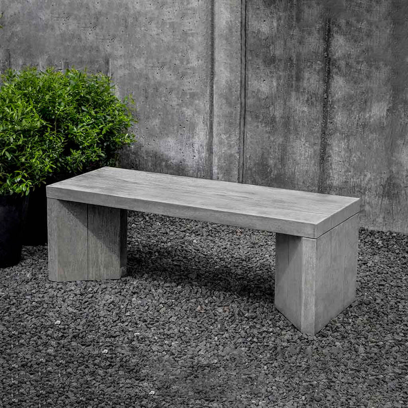Campania International Chenes Brut Bench, set in the garden to adding charm and purpose. The bench is shown in the Greystone Patina.