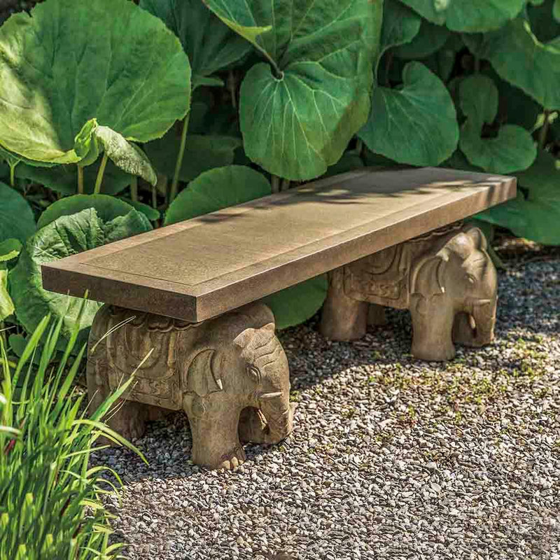Campania International Elephant Bench, set in the garden to adding charm and purpose. The bench is shown in the Aged Limestone Patina.