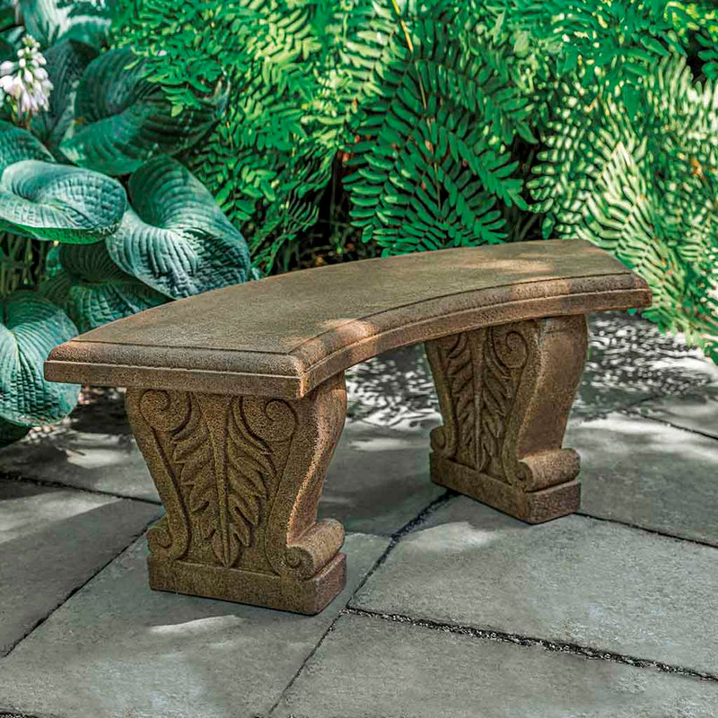 Campania International Soledad Bench, set in the garden to adding charm and purpose. The bench is shown in the Aged Limestone Patina.