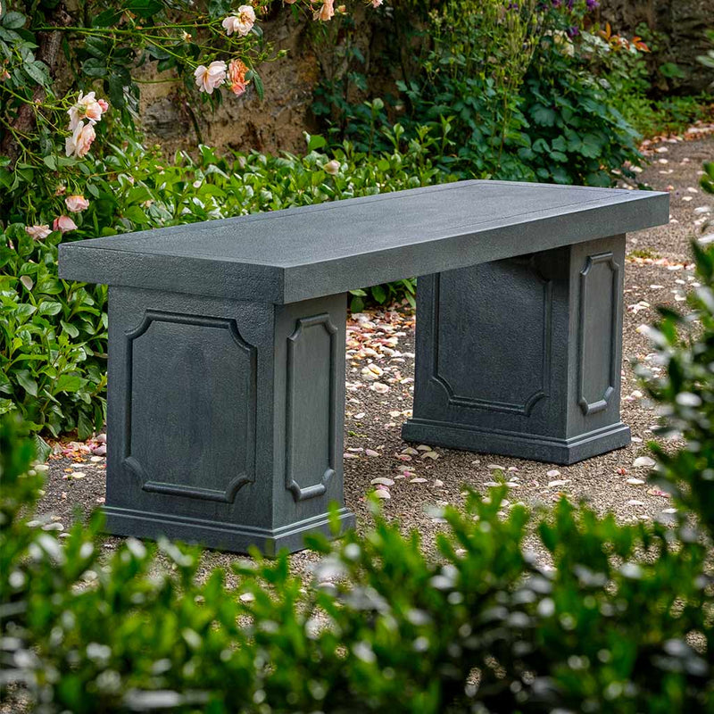 Campania International Cumberland Bench, set in the garden to adding charm and purpose. The bench is shown in the Lead Antique Patina.