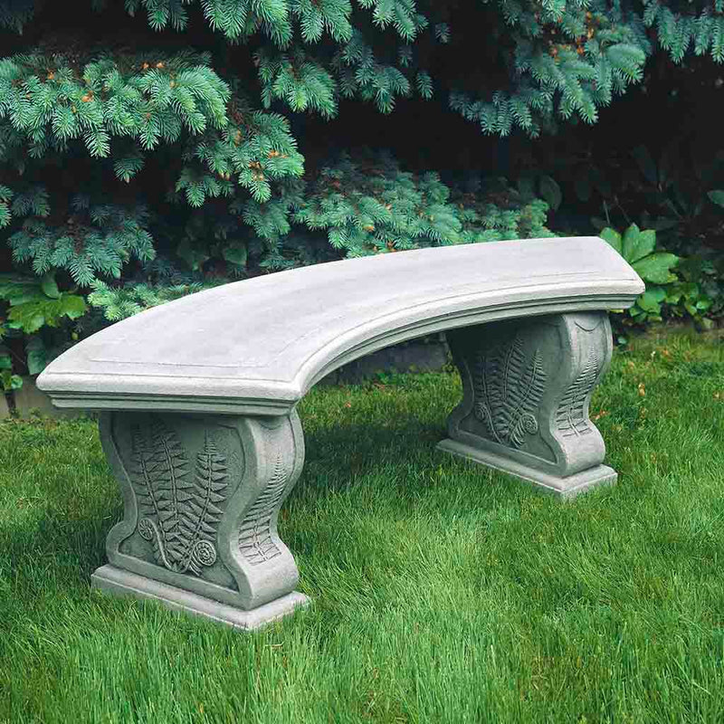 Campania International Curved Woodland Ferns Bench, set in the garden to adding charm and purpose. The bench is shown in the Greystone Patina.