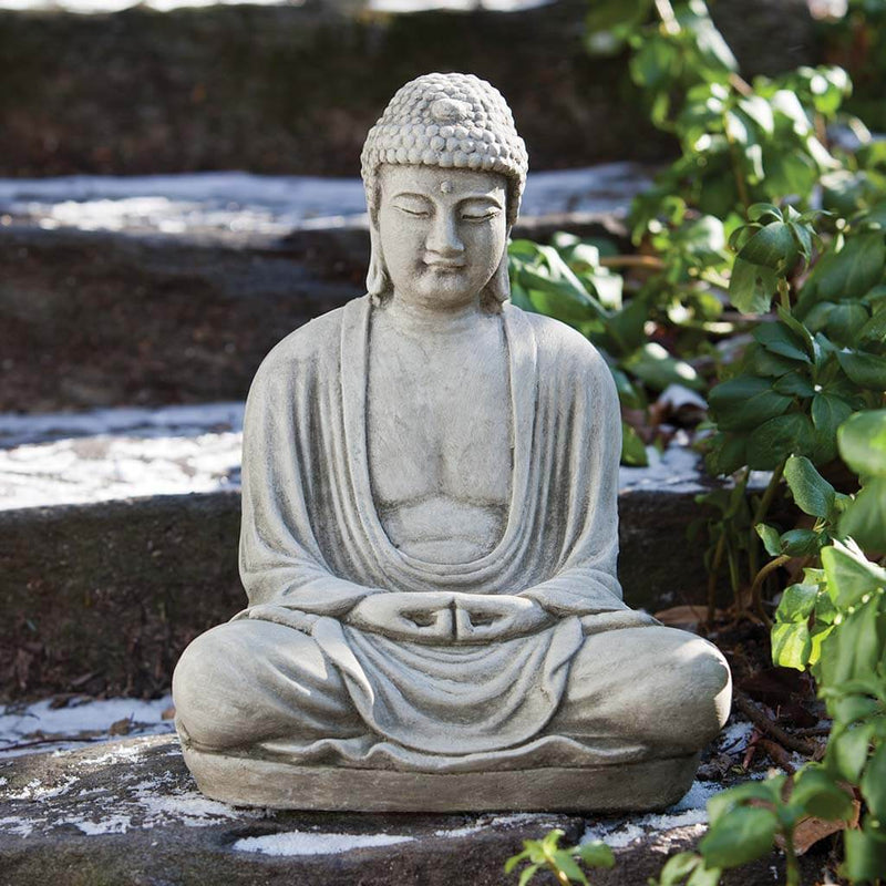 Campania International Small Temple Buddha Statue, set in the garden to adding charm an meaning. The statue is shown in the Greystone Patina.