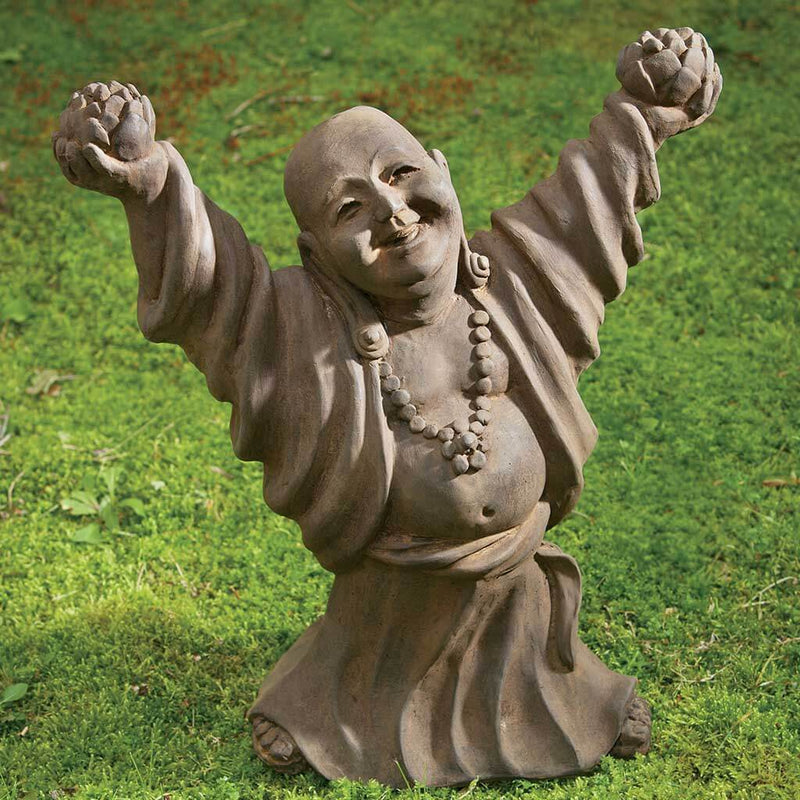 Campania International Dancing Buddha Statue, set in the garden to adding charm an meaning. The statue is shown in the Pietra Nuova Patina.