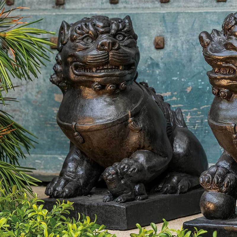 Campania International Traditional Foo Dog Female Statue, set in the garden to adding charm an meaning. The statue is shown in the Nero Nuovo Patina.