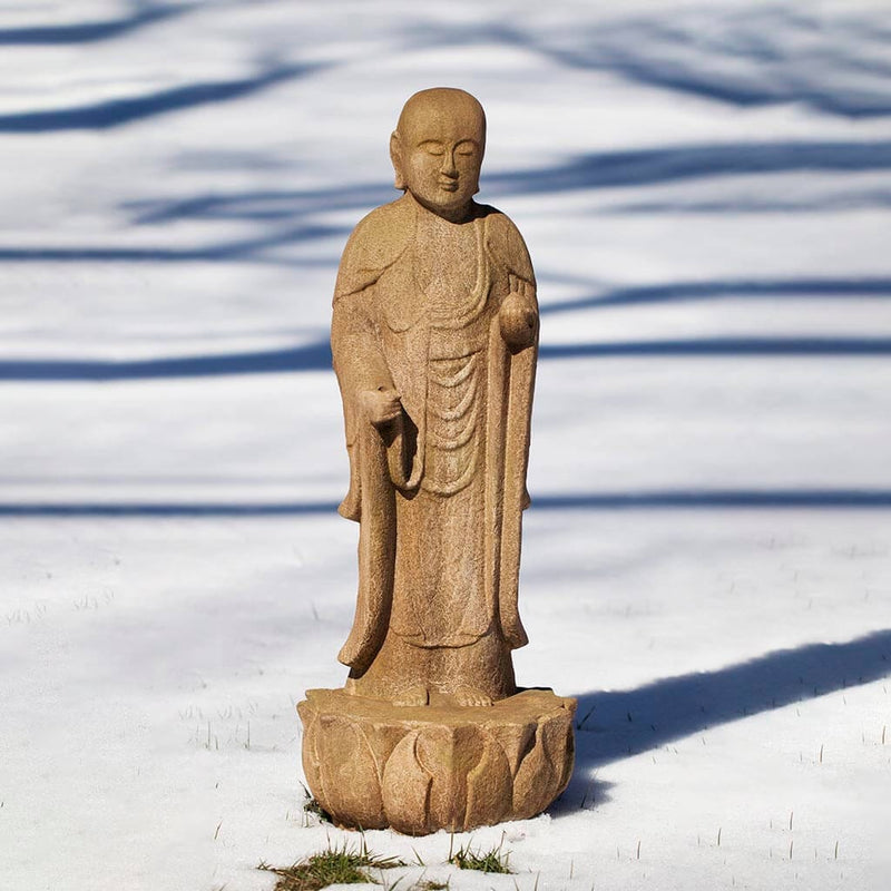 Campania International Morris Standing Buddha, set in the garden to adding charm an meaning. The statue is shown in the English Moss Patina.