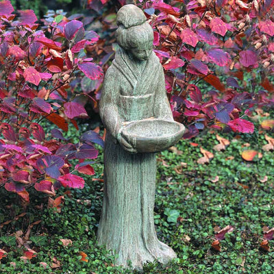 Campania International Oriental Maiden with Bowl, set in the garden to adding charm an meaning. The statue is shown in the Copper Bronze [pPatina.
