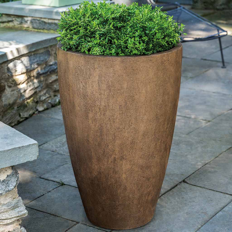 Campania International Series 3 - 19 x 29 Planter, filled with soft foliage, ideal for entryways or patios, shown in the Pietra Nuova Patina. Made from cast stone.