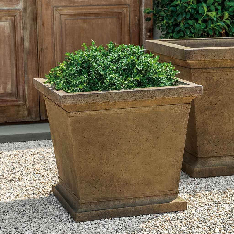 Campania International Madison Planter, filled with soft foliage, ideal for entryways or patios, shown in the Aged Limestone Patina. Made from cast stone.