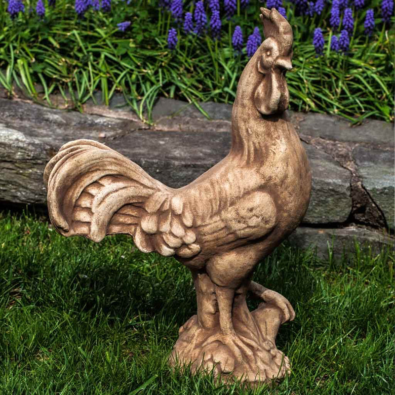 Campania International Antique Rooster Statue, set in the garden to add charm and character. The statue is shown in the Brownstone Patina.