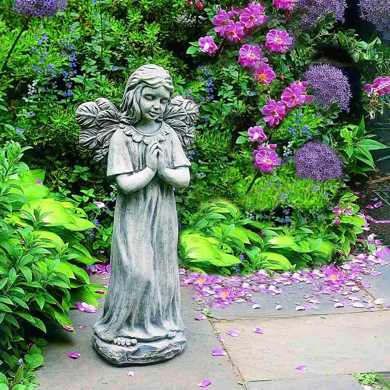 Campania International Praying Angel Statue placed in the garden. Religious garden statues, made of cast stone in a range of color options.