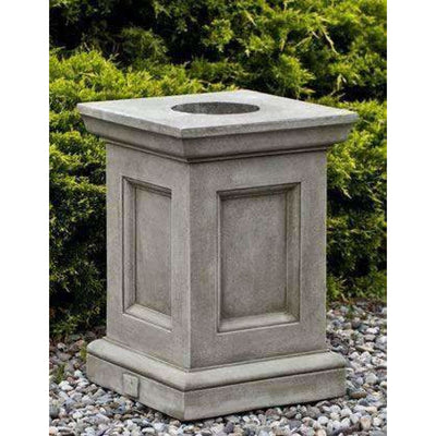 Campania International Barnett Pedestal, set in the garden elevate a statue or planter. The pedestal is shown in the Greystone Patina.