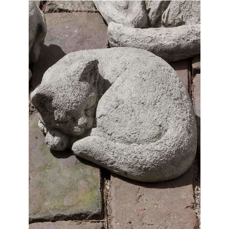 Campania International Curled Small Cat Statue, set in the garden to add charm and character. The statue is shown in the Greystone Patina.
