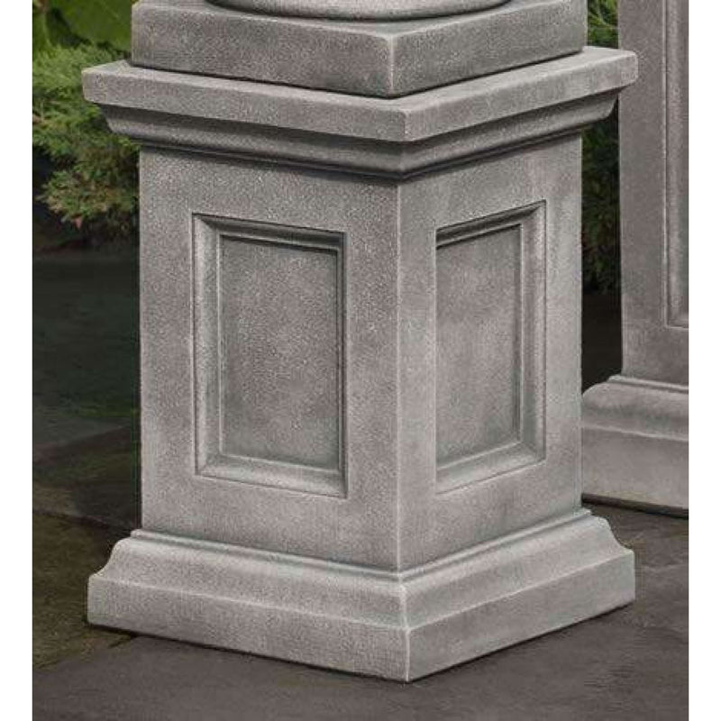 Campania International Lenox Pedestal, set in the garden elevate a statue or planter. The pedestal is shown in the Greystone Patina.