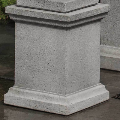 Campania International Wolcott Pedestal, set in the garden elevate a statue or planter. The pedestal is shown in the Alpine Stone Patina.