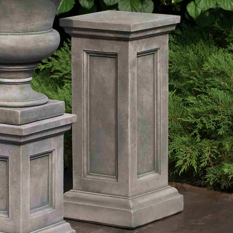 Campania International Lenox Tall Pedestal, set in the garden elevate a statue or planter. The pedestal is shown in the Alpine Stone Patina.